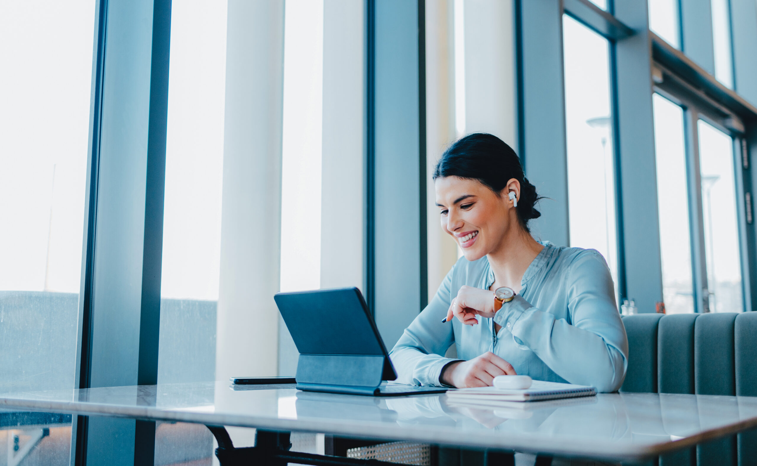 A female employee sitting in her office and looking at her computer while smiling.